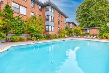 A swimming pool in front of a red brick building.